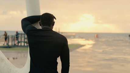 Back view of man resting between exercises during street workout by the sea, active lifestyle,...