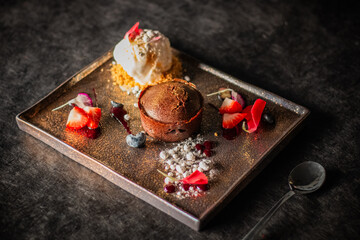 A dessert plate with a chocolate lava cake, ice cream, fresh strawberries