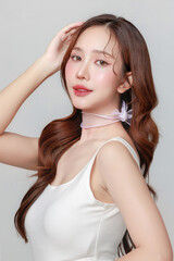 Obraz premium Pretty Asian woman model perfect clear fresh skin smile on isolated grey background. Portrait female beauty blogger make up artist in studio. Skincare, plastic surgery, spa concept.