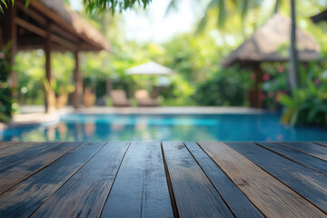 A serene poolside view with wooden table and lush greenery in the background.