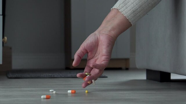 Close up hand elderly woman drops pills from palm hand to floor, illustrating problems drug treatment and difficulties sick people. Loss of consciousness due to overdose and abuse of medical services