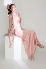 Stylish young fashionable Asian woman in a stunning pink dress, trendy makeup with light shining...