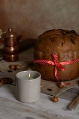 Traditional Italian Christmas Cake Panettone with red bow and lit candle on wooden rustic table background. Homemade artisan sourdough panettone ready for eating. Classic Christmas Food Edible gift