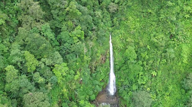 Aerial shot of Curug Cijalu ,beautiful hidden waterfall in green forest. Tropical mountain jungle waterfall in the tropical forest. Nature background