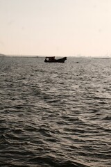 Naklejka premium Serene Seascape Boat on Rippled Water Coastal View