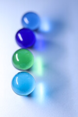 colorful glass marbles dropping colorful reflection on white background	