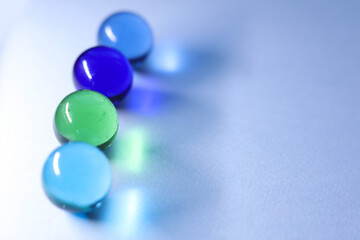 colorful glass marbles dropping colorful reflection on white background