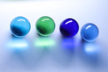 colorful glass marbles dropping colorful reflection on white background