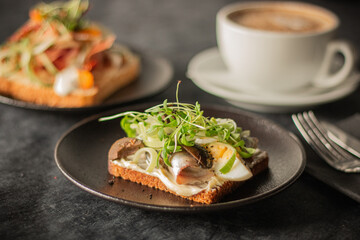 A close-up of a rustic toast topped with herring, boiled egg, greens