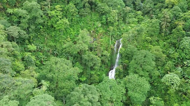 Aerial shot of Curug Cijalu ,beautiful hidden waterfall in green forest. Tropical mountain jungle waterfall in the tropical forest. Nature background