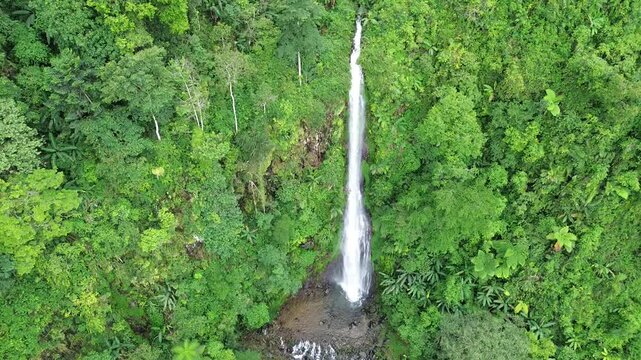 Aerial shot of Curug Cijalu ,beautiful hidden waterfall in green forest. Tropical mountain jungle waterfall in the tropical forest. Nature background