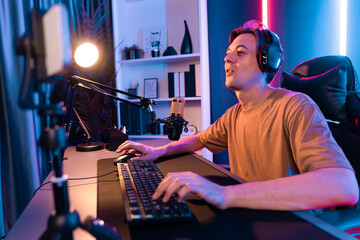 Host channel of gaming smart streamer playing online game to be winner, wearing headphone with viewers live steaming on media social online for selected team competition at neon light room. Pecuniary.