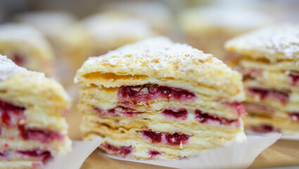 A delicious dessert made of puff pastry with raspberry layers and cream, close-up view