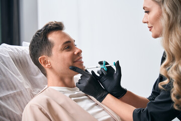 Woman beautician making botulinum toxin injections into client's chin