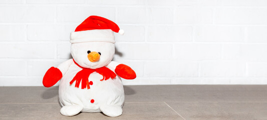 Snowman toy on the background of a white brick wall, copy space. New Year and Christmas