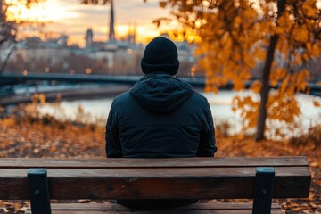 A solitary figure sits on a bench, gazing at a city sunset, embodying feelings of reflection, solitude, and a deep connection to the vibrant beauty of urban life.