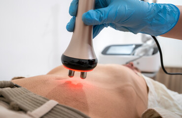 A man is getting a massage with a red light on his stomach