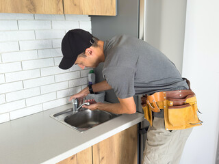 Worker installs faucet for kitchen sink.