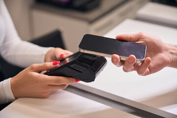 Female receptionist suggesting pos terminal to client who paying contactless