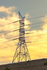 Photograph of a large electricity Transmission Tower on a grassy hill against an orange sunset sky in regional Australia.