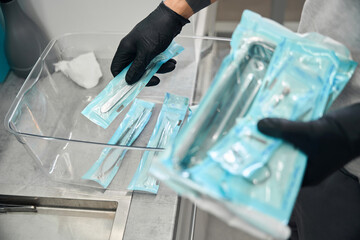 Dental technician in rubber gloves taking packages with sterile tools