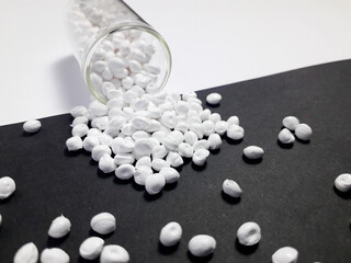 Opaque white masterbatch granules with glass tube on black and white background,color pigment carrier polymer in plastic industry,suitable for plastic company catalog design