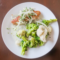 meat cutlet with onion, cauliflower and broccoli on a plate on a wooden table