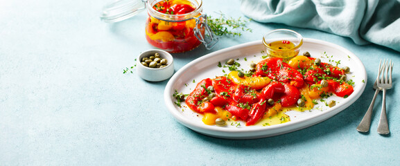 Marinated yellow and red bell pepper salad with capers and olive oil. Blue background. Copy space.