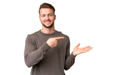 Young handsome caucasian man over isolated chroma key background holding copyspace imaginary on the...