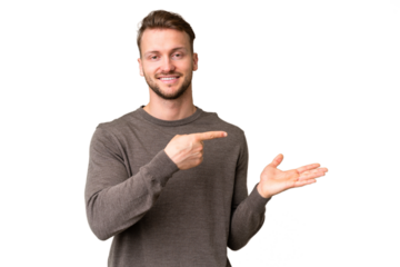 Young handsome caucasian man over isolated chroma key background holding copyspace imaginary on the palm to insert an ad