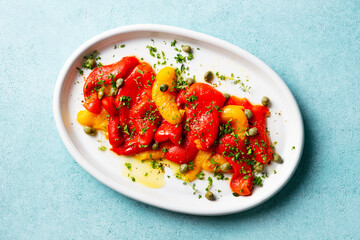 Grilled sweet pepper salad on a white plate. Blue background. Close up. Top view.