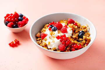 Healthy breakfast. Granola, muesli with yogurt and fresh berries. Pink background. Close up.