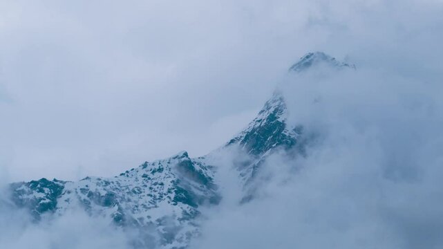 4k Time Lapse of Moving Fog, clouds and Mist over snow covered mountain peak in Keylong, Lahaul, India. Beautiful scenic landscape of Himalayas in winter. 