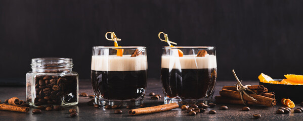 Spanish coffee cocktail with cinnamon and orange zest in glasses on table web banner