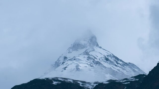 4K Zoom in timelapse of clouds moving around snowy mountain peak in Lahaul, Himachal Pradesh, India. Winter travel background. Nature landscape. Ken Burn effect
