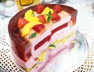 A slice of jelly cake with strawberries and peaches on top