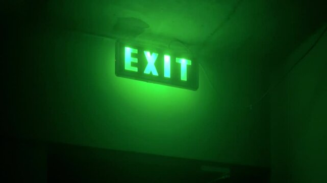 Horizontal video. Fire exit sign in house. Green light. Glowing inscription. Concept of emergency, problem solving, trip, fear, horror, gestalt psychology. Led lamp. Copy space. Hotel. Entrance door