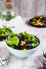 Red cabbage, corn and arugula salad in a bowl on the table vertical view