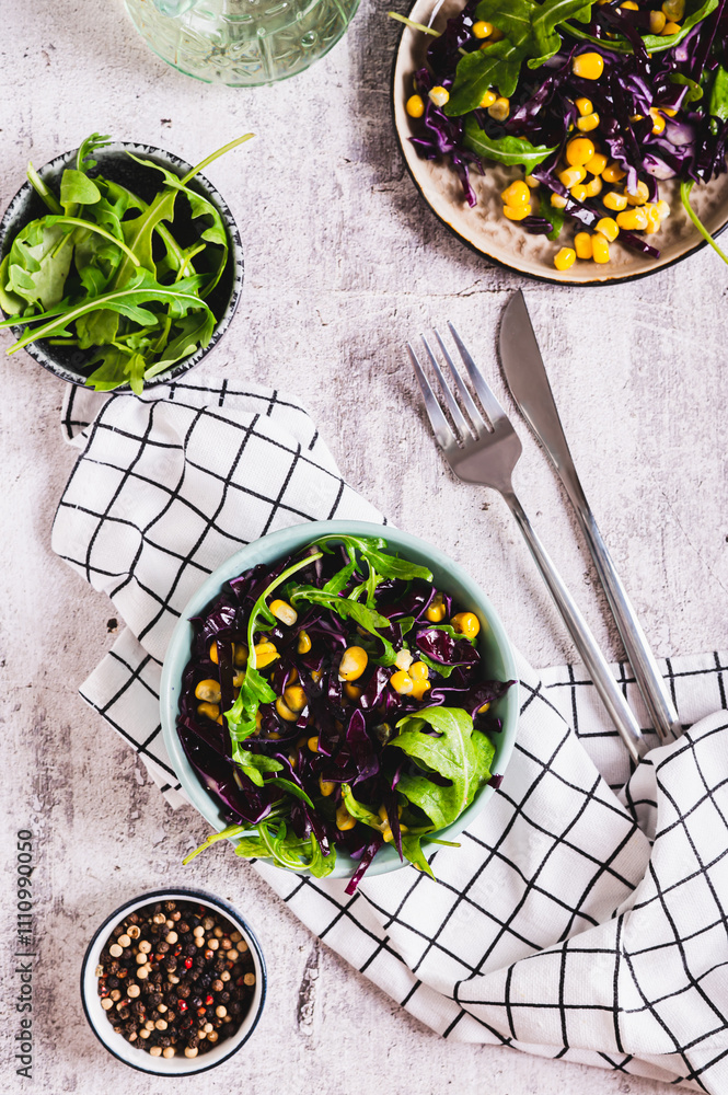 Wall mural Vegetarian salad of purple cabbage, corn and arugula in a bowl top and vertical view