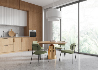 Modern kitchen interior with wooden cabinets, round dining table with green chairs, and large windows overlooking nature. . 3D Rendering