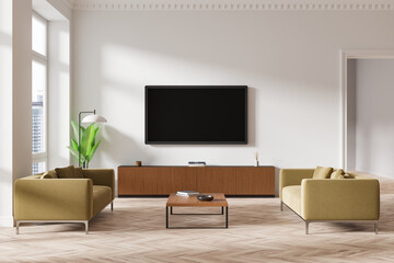Modern living room interior with green sofas, minimalistic furniture, and large TV on wall in...