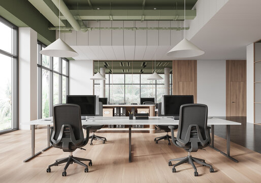 Modern coworking space interior with minimalist office furniture, computer desks, and chairs in a spacious loft-style room with large windows. 3D Rendering