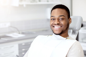 Dental Clinic Concept. Portrait Of Joyful Young Black Guy Sitting In Chair Iin Stomatological...