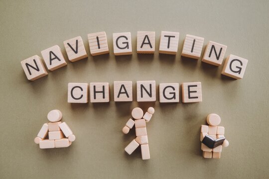 Wooden blocks spell out 'Navigating Change' with figures representing different approaches to change