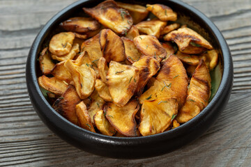 Homemade parsnip chips in bowl on rustic wooden table.