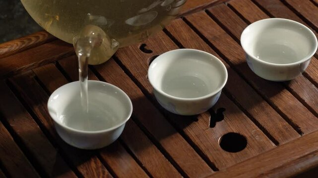 Tea ceremony on dark background. Pouring green tea in cup. 