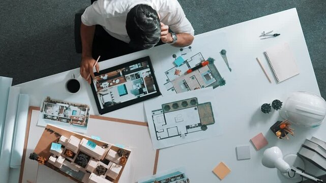Top view of engineer drink coffee and thinking about house plan at meeting table with equipment and safety helmet scatter around. Aerial view of stressful manager looking at blueprint. Alimentation.