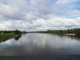 Scenic river view with stadium and bridge under cloudy sky in Warsaw