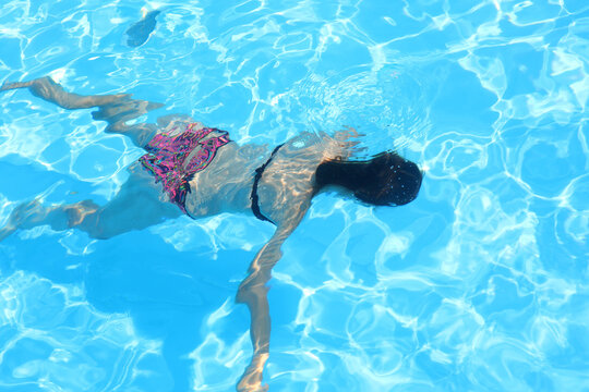 girl lying motionless at the bottom of the pool with water