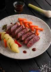 Grilled beef steaks and vegetables, With cooked carrots and mashed potatoes, black wood background